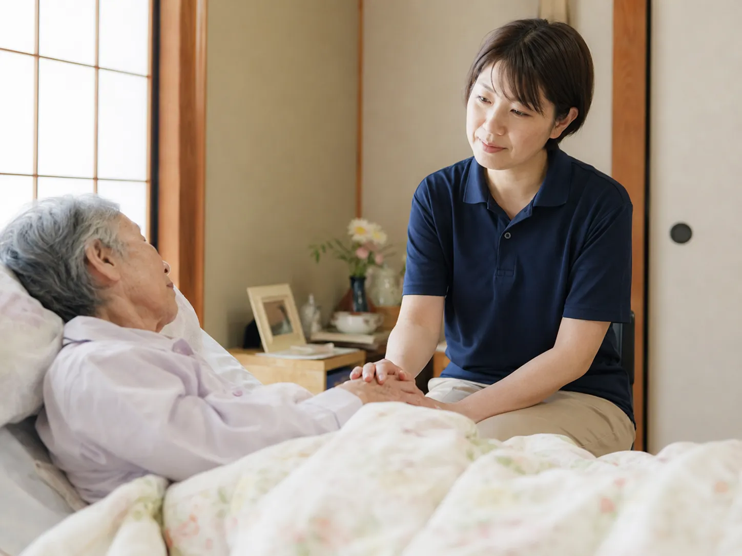 ベッドで手を取り寄り添う看護師と利用者