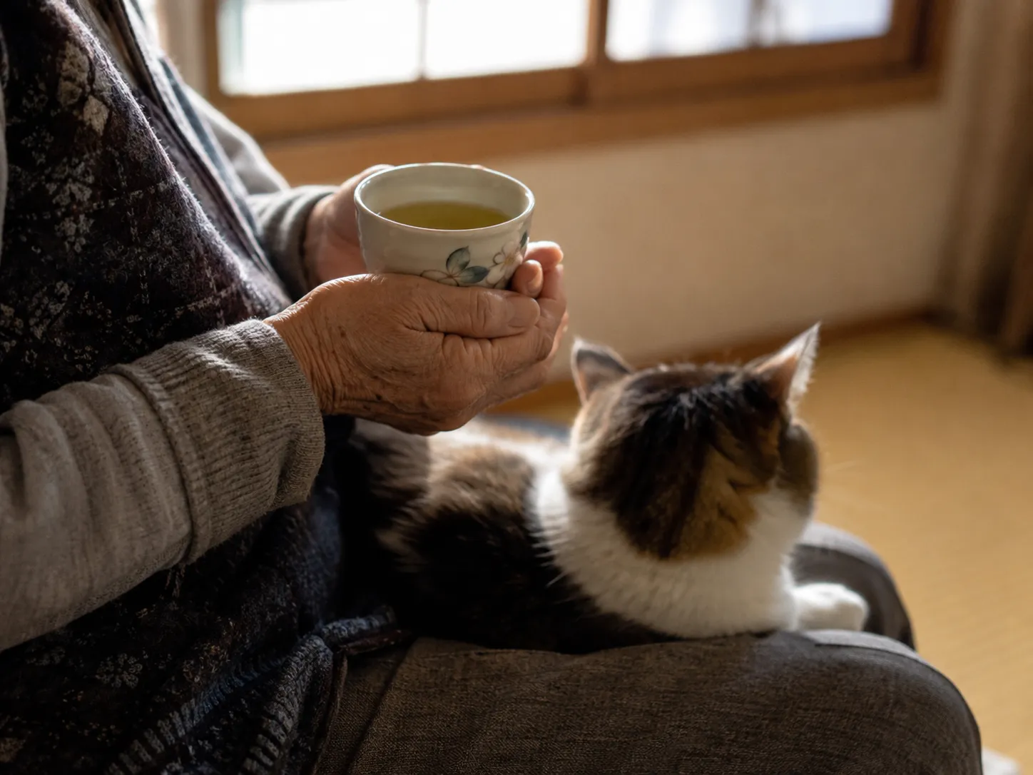 猫とくつろぎながら湯のみを手にする利用者