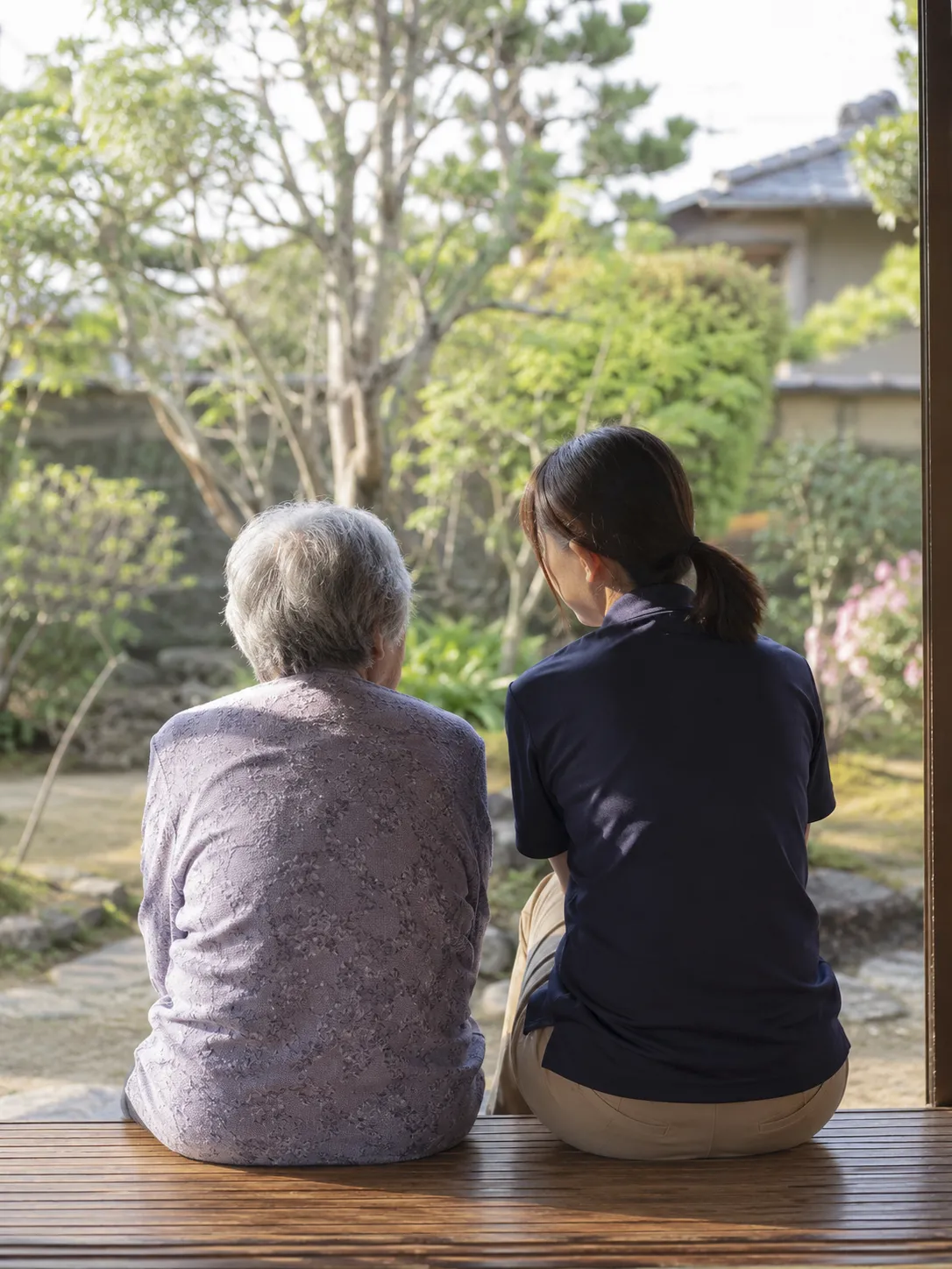 庭を眺めながら縁側に座る利用者と看護師